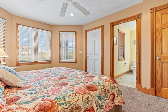 bedroom with ensuite bathroom, light tile patterned flooring, a ceiling fan, and baseboards