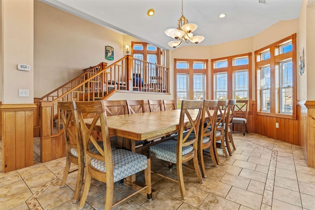 dining space with vaulted ceiling, a wainscoted wall, a notable chandelier, and wooden walls