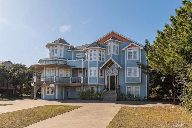 view of front facade featuring concrete driveway and a balcony