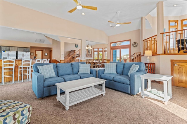 living room featuring stairs, recessed lighting, light colored carpet, high vaulted ceiling, and ceiling fan with notable chandelier