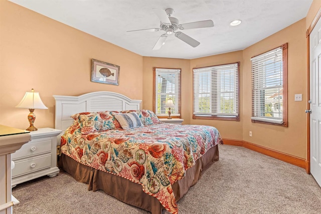 bedroom with multiple windows, ceiling fan, light carpet, and baseboards