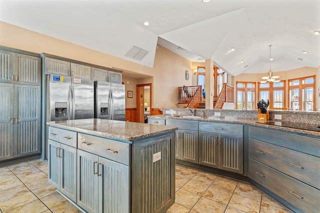 kitchen featuring light stone counters, stainless steel refrigerator with ice dispenser, lofted ceiling, visible vents, and a kitchen island