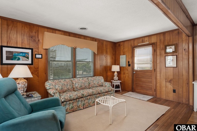 living room featuring visible vents, wooden walls, and wood finished floors