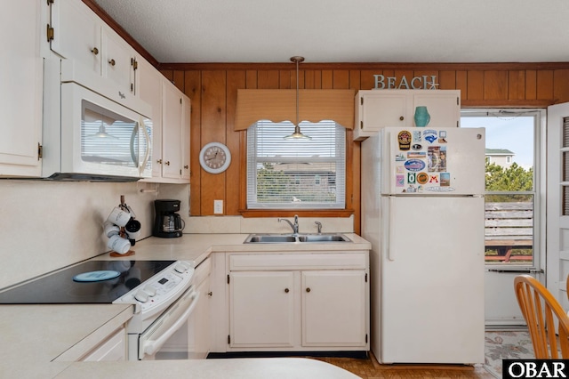 kitchen featuring white appliances, light countertops, a sink, and white cabinets