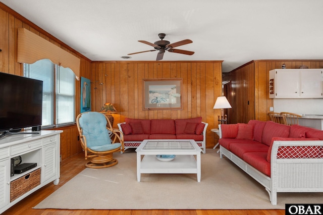 living area featuring ceiling fan, wooden walls, and wood finished floors