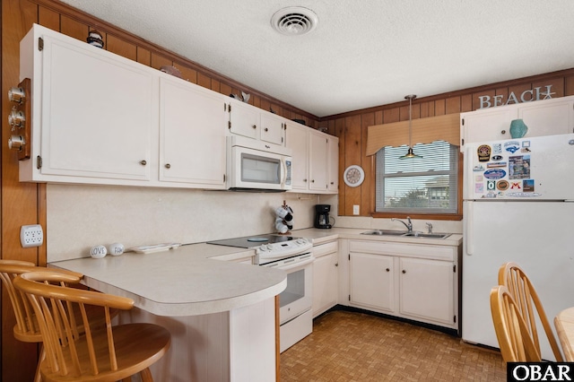 kitchen with light countertops, visible vents, a sink, white appliances, and a peninsula