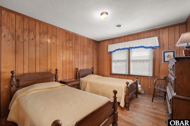 bedroom with light wood-type flooring, visible vents, and a textured ceiling