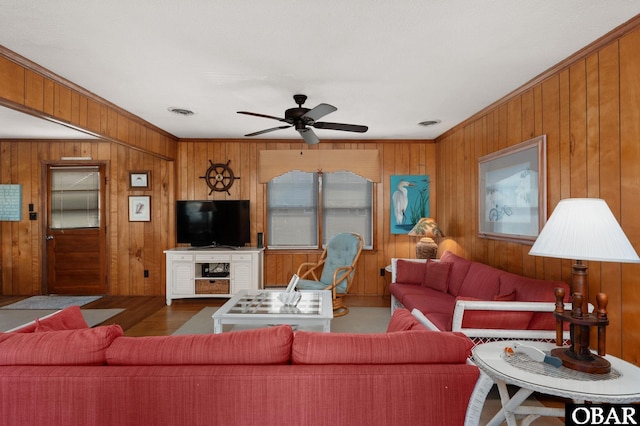 living area featuring visible vents, a ceiling fan, wood finished floors, crown molding, and wood walls