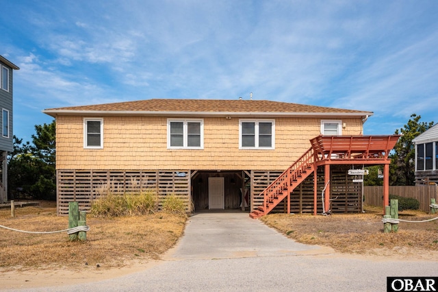 view of front of house with a shingled roof, stairs, a carport, and concrete driveway