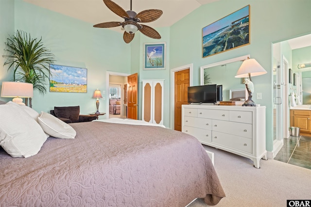 carpeted bedroom featuring high vaulted ceiling and ensuite bath