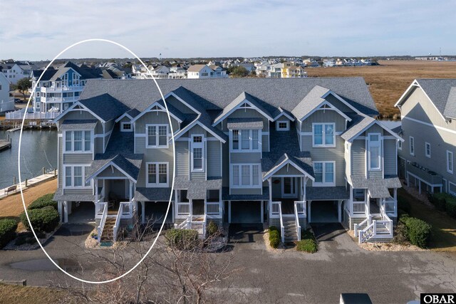 view of front of house featuring a residential view, a water view, and roof with shingles