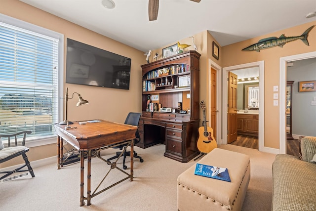 office area with a ceiling fan, light colored carpet, and baseboards