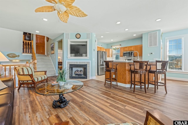 living area with light wood-style flooring, a fireplace, baseboards, and recessed lighting