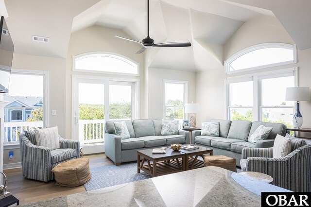 living area with high vaulted ceiling, wood finished floors, visible vents, and a ceiling fan