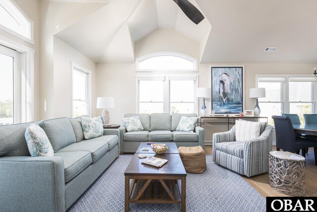 living area featuring high vaulted ceiling, a wealth of natural light, visible vents, and light wood-style floors