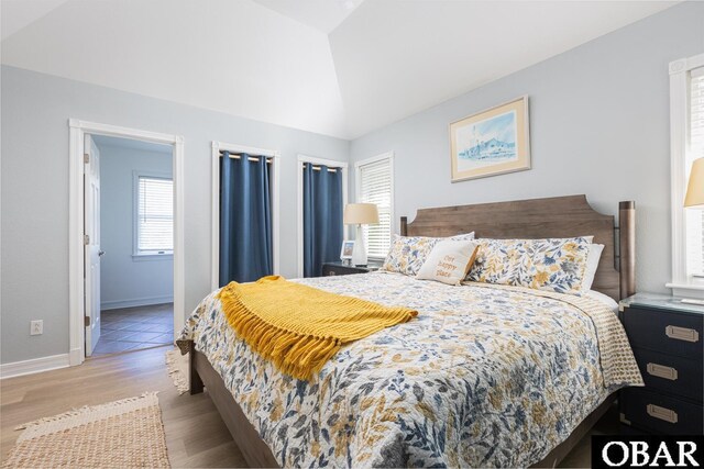 bedroom featuring light wood-style floors, baseboards, and vaulted ceiling