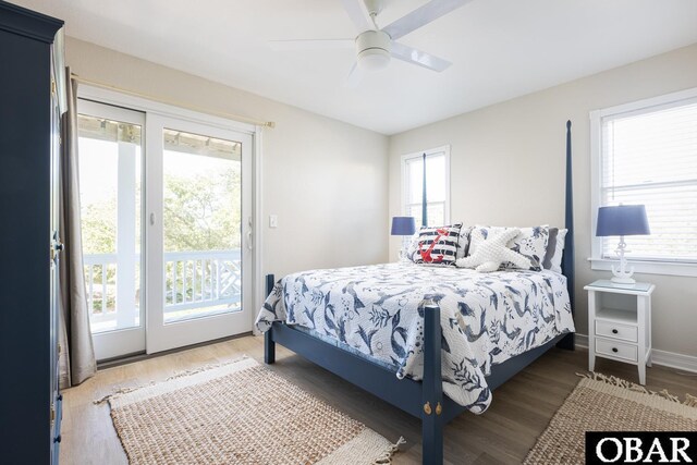 bedroom with baseboards, dark wood-type flooring, multiple windows, and access to exterior