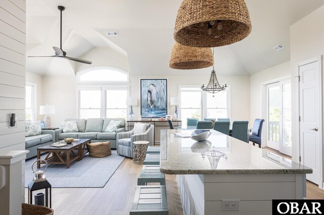 dining area featuring high vaulted ceiling, light wood-style flooring, visible vents, and a wealth of natural light