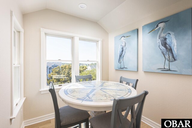 dining area with vaulted ceiling, wood finished floors, and baseboards