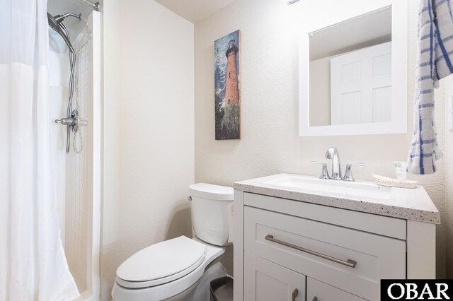 bathroom featuring toilet, a shower stall, and vanity