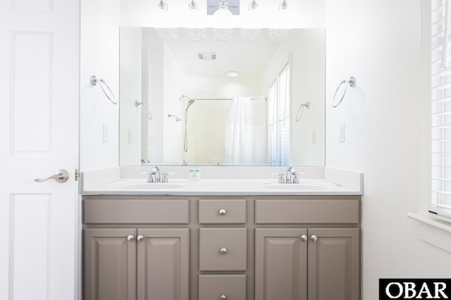 bathroom featuring visible vents, a sink, a shower with shower curtain, and double vanity