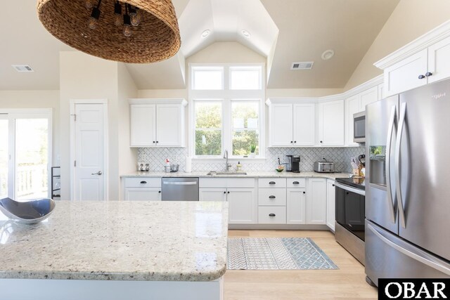 kitchen with visible vents, white cabinets, light stone counters, appliances with stainless steel finishes, and a sink