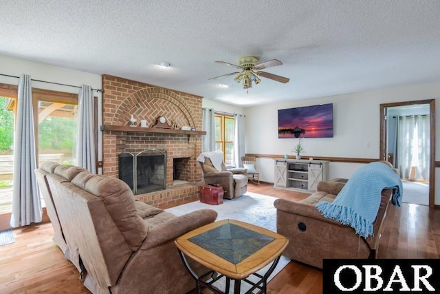 128 Daphne Ln Lot 17, Manteo, NC 27954 - living room with a textured ceiling, ceiling fan, light wood-style floors, and a brick fireplace