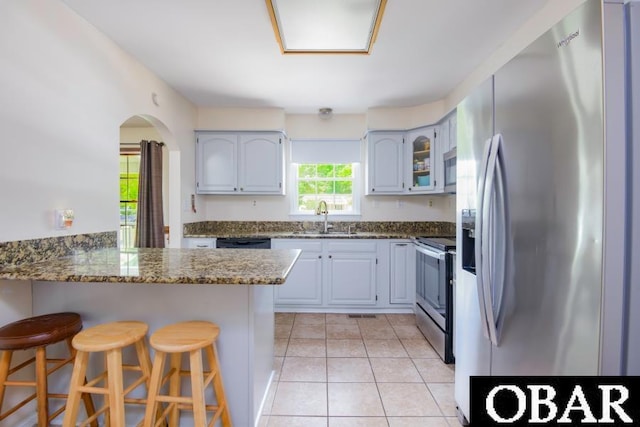 128 Daphne Ln Lot 17, Manteo, NC 27954 - kitchen with appliances with stainless steel finishes, a peninsula, a kitchen bar, dark stone countertops, and light tile patterned flooring