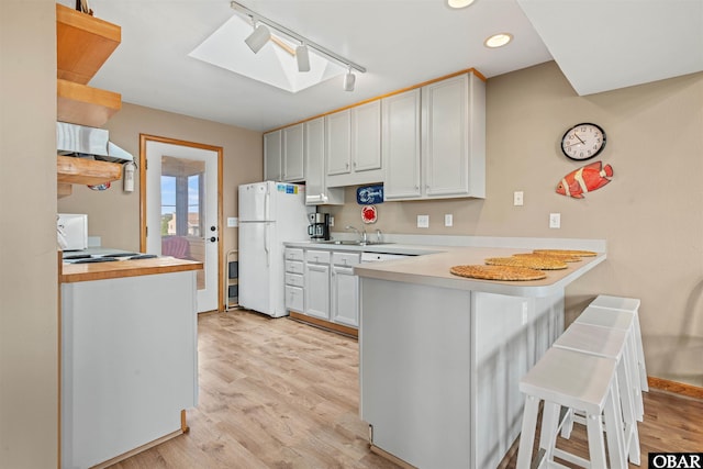 kitchen featuring white cabinets, light countertops, a peninsula, and a breakfast bar area