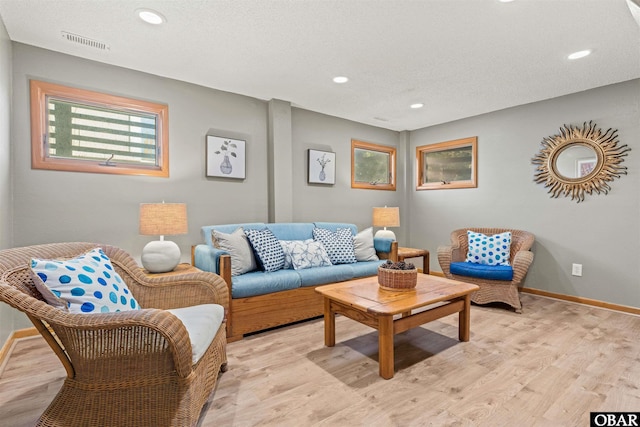 living area with light wood-type flooring, visible vents, and baseboards