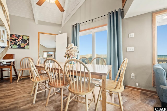 dining space featuring lofted ceiling with beams, ceiling fan, wood finished floors, and baseboards