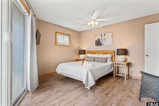 bedroom featuring light wood finished floors, a ceiling fan, baseboards, and a textured ceiling