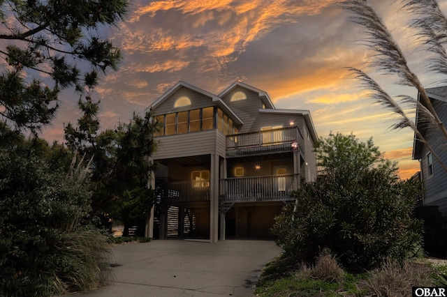 coastal inspired home with a balcony, covered porch, driveway, stairway, and a carport