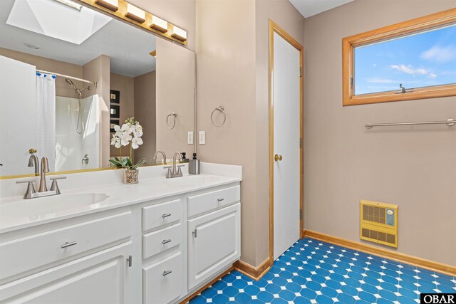 bathroom with double vanity, heating unit, a sink, and baseboards