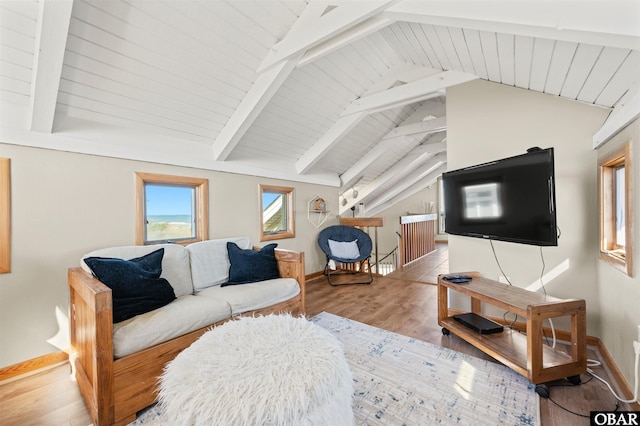 living area featuring vaulted ceiling with beams, light wood-type flooring, and baseboards