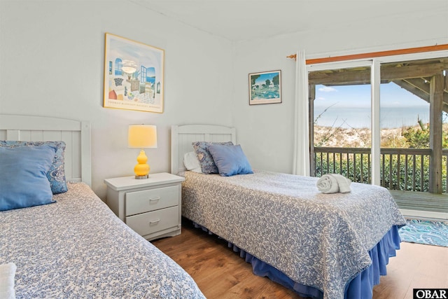 bedroom featuring access to outside, a water view, and dark wood finished floors