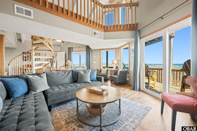 living room featuring a water view, stairs, visible vents, and wood finished floors