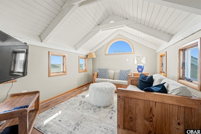 living room with vaulted ceiling with beams, wood finished floors, and a wealth of natural light