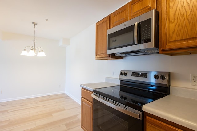 kitchen with pendant lighting, brown cabinets, light wood finished floors, stainless steel appliances, and light countertops