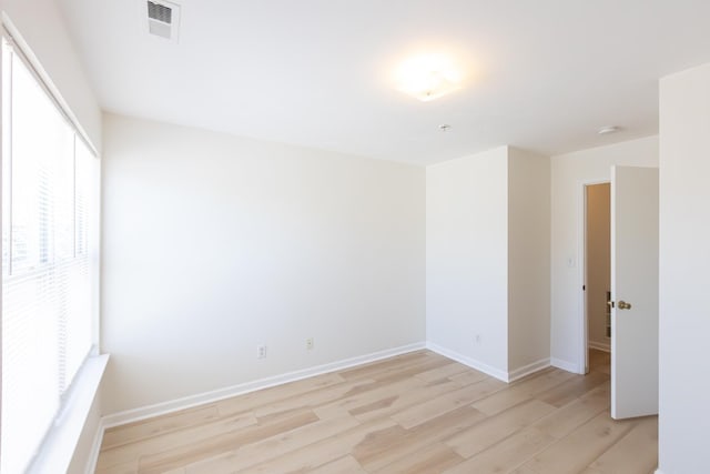 spare room featuring light wood-style floors, visible vents, and baseboards