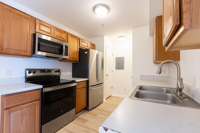 kitchen featuring stainless steel appliances, light wood-style flooring, a sink, and light countertops