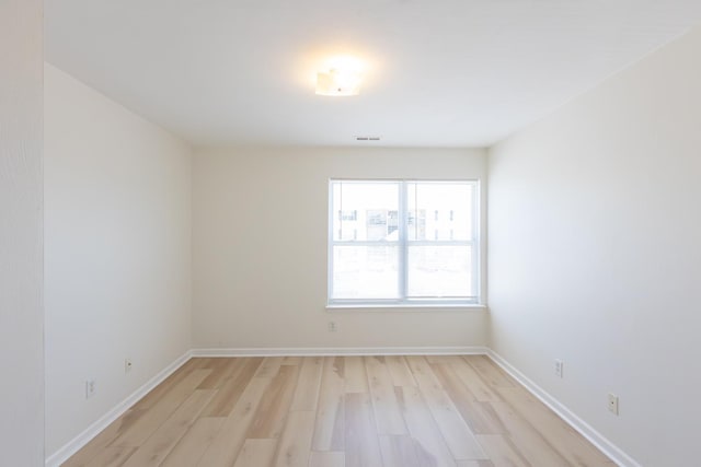 spare room with baseboards, visible vents, and light wood-style floors