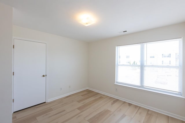 empty room featuring baseboards, visible vents, and light wood finished floors