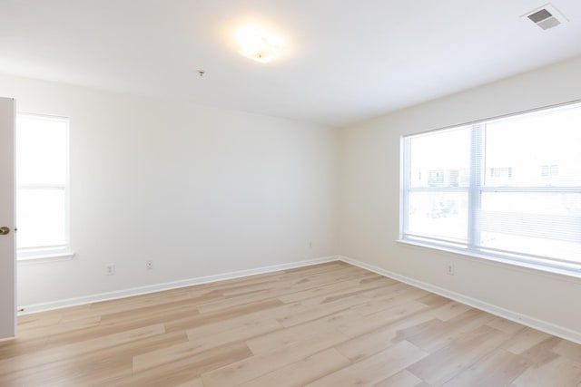 unfurnished room featuring light wood-style flooring, visible vents, and baseboards