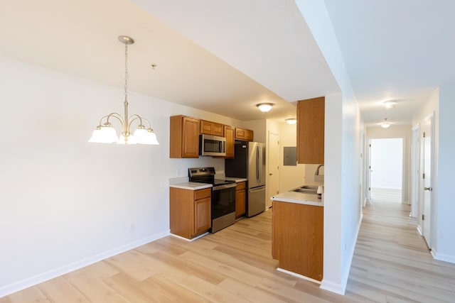 kitchen featuring pendant lighting, brown cabinets, light countertops, appliances with stainless steel finishes, and a sink