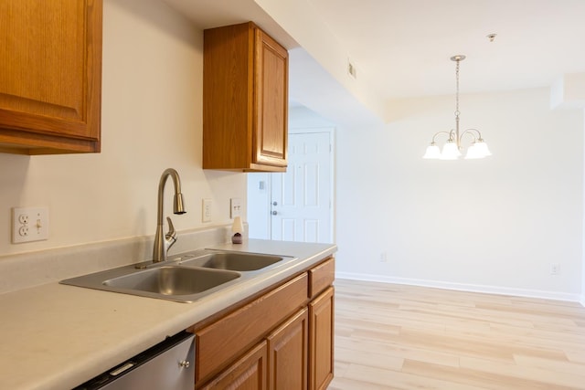 kitchen featuring a sink, light countertops, light wood-type flooring, brown cabinets, and pendant lighting