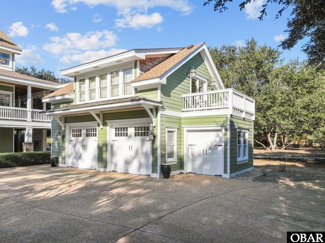 view of front of home with a garage, a balcony, driveway, and a shingled roof