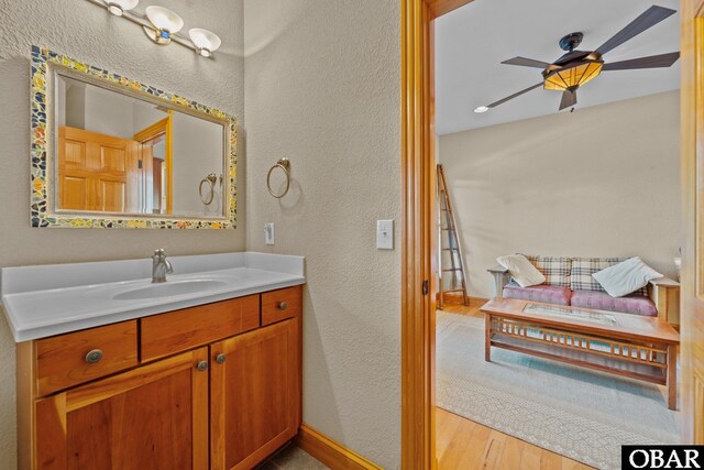 bathroom featuring a textured wall, wood finished floors, vanity, and a ceiling fan