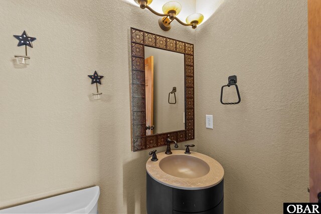 half bath with toilet, a sink, and a textured wall