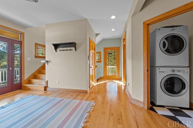 foyer with light wood finished floors, stairway, stacked washer / dryer, and plenty of natural light